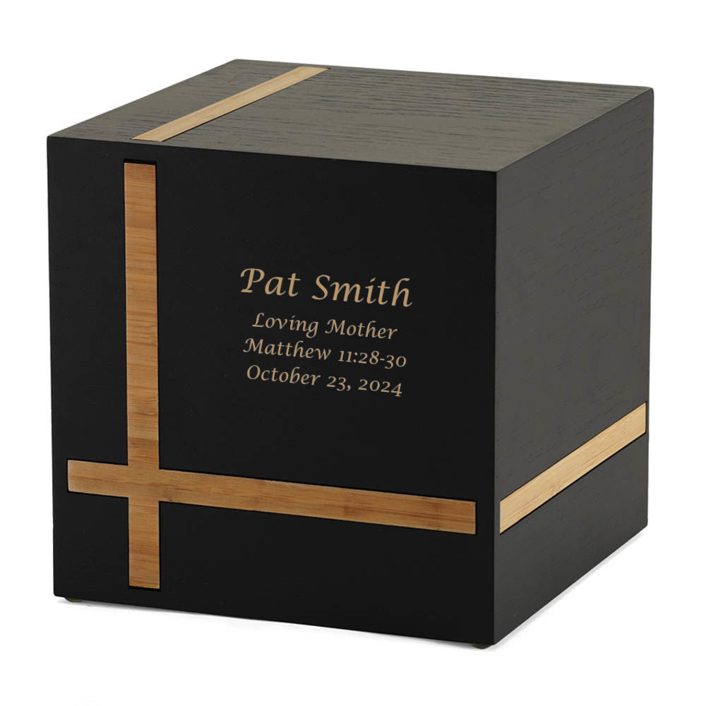 Bristol Ebony/Bamboo Extra-Large Cremation Urn featuring a personalized engraving. The urn has a sleek black MDF finish with warm bamboo inlays forming a contemporary geometric design. Its cube shape and minimalist style make it ideal for home display. The urn is secured with a sliding bottom panel. Custom engraving is available. 245 cubic inch capacity