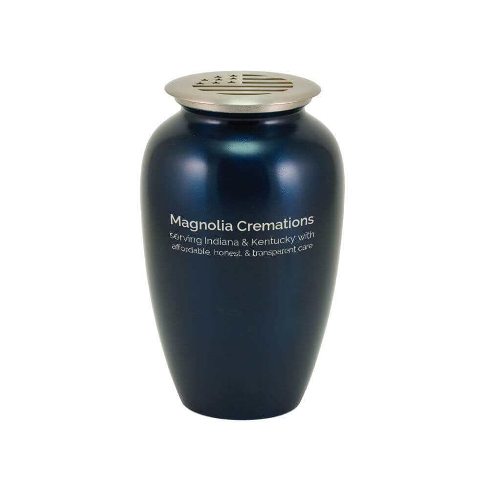 A dark blue scattering urn with a silver-toned lid that features a cutout design of the American flag. The front of the urn is printed with the text: "Magnolia Cremations – serving Indiana & Kentucky with affordable, honest, & transparent care."