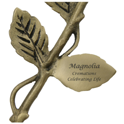 The Crimson Rose Keepsake, available at Magnolia Cremations, features a detailed brass stem with textured leaves and a customizable engraved plaque. This elegant memorial piece is designed to hold a nominal amount of ashes, offering a lasting tribute to a loved one.