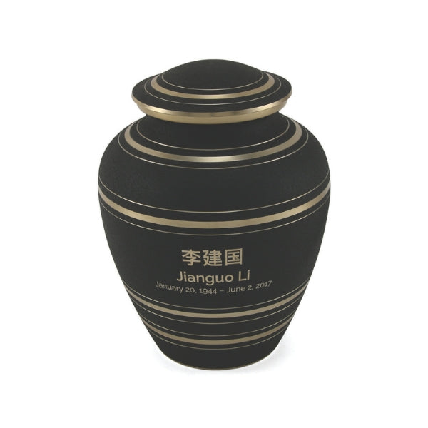 A full view of a matte black memorial urn with gold accent stripes. The urn has an engraved name and dates in both Chinese characters and English. The lid features matching gold bands. Engraving is available for personalization.
