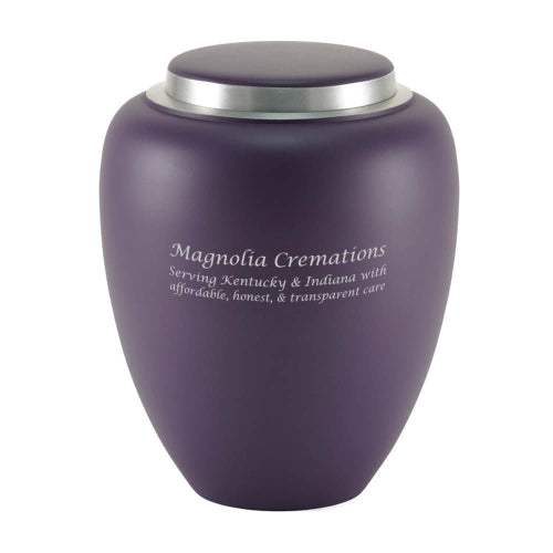A modern memorial urn with a matte amethyst purple finish and a silver-toned lid. The urn features engraving, which is available for personalization.