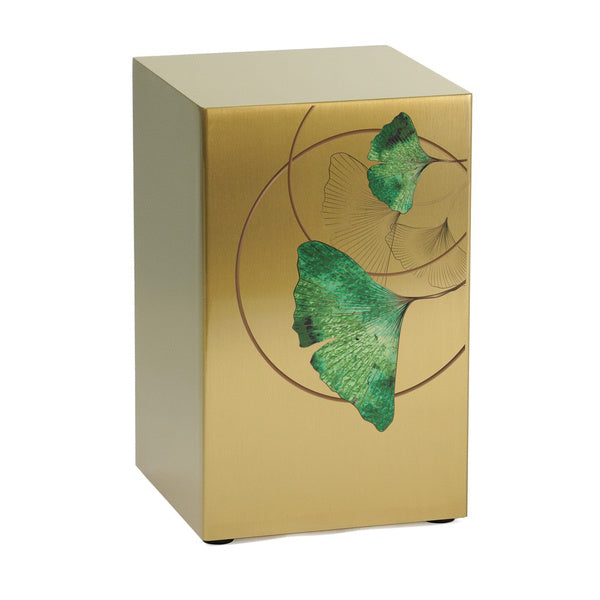 A golden memorial urn with a contemporary design featuring an artistic ginkgo leaf motif. The urn has a brushed metallic finish, with green and gold-toned leaves accented by delicate circular linework. It is designed as a standalone piece or as part of a companion set.