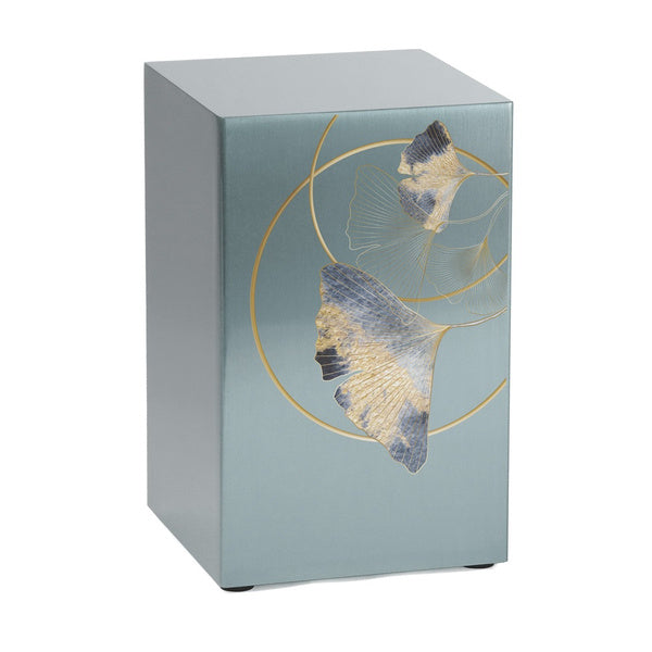A silver-colored companion urn with an intricate ginkgo leaf design, featuring a brushed stainless steel finish with gold detailing and textured blue and gold leaves. Designed for individual use or as part of a paired set. Engraving is available.