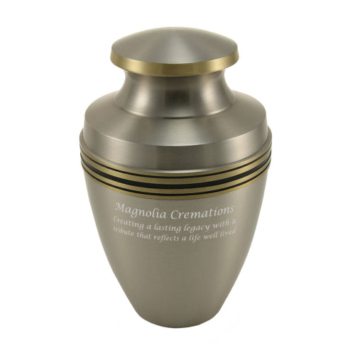 A Grecian Pewter memorial urn with a brushed silver finish, accented by gold and black decorative bands near the top. The urn has a classic, elegant shape with a rounded lid and a smooth, polished surface. Engraving is displayed on the front, offering personalization options for a meaningful tribute. Crafted from high-quality brass, this cremation urn provides a timeless and sophisticated resting place for a loved one.