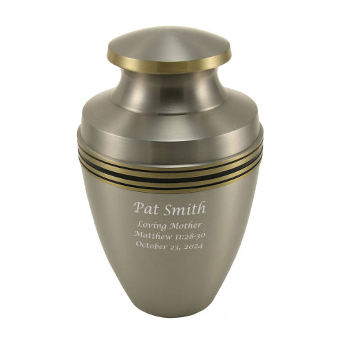 A brushed silver cremation urn with gold accent bands, featuring a gently curved shape and a polished lid. The urn is engraved with a personalized tribute, highlighting its availability for customization. Its classic Grecian-inspired design offers a timeless and dignified way to honor a loved one’s memory.