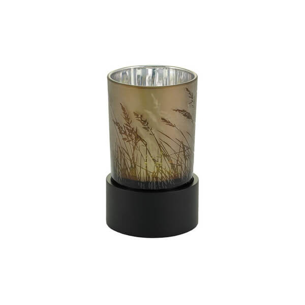 Keepsake urn designed as a tealight candle holder, featuring a frosted glass cup with a printed design of tall grasses in warm earth tones, resting on a black circular base.