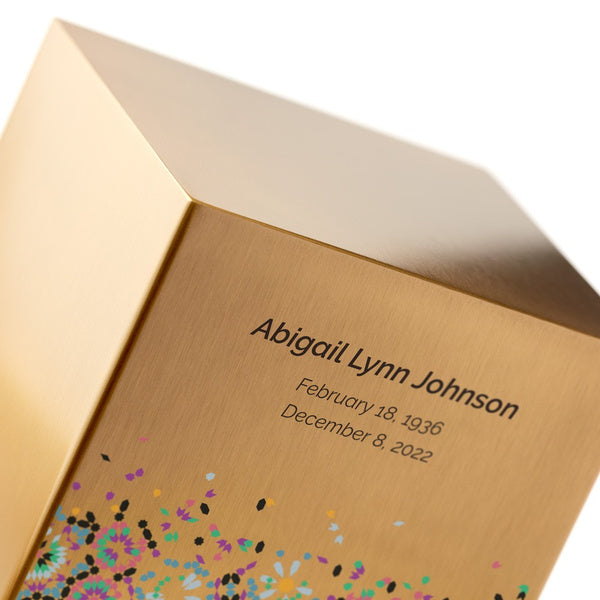 A close-up of the Magnolia Cremations Mosaic in Bronze Memorial Urn, highlighting its brushed bronze-tone stainless steel finish and intricate mosaic-inspired design. Engraving is shown as an available option, adding a personal touch to this contemporary memorial piece.