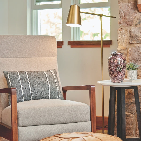 The Magnolia Cremations Mossy Oak Camo Memorial Urn sits elegantly on a modern side table, its lifelike woodland pattern blending seamlessly with the warm, rustic ambiance of the room. With earthy tones of bark, pine, and leaves, this urn serves as a fitting tribute to a nature lover, offering a timeless connection to the great outdoors.