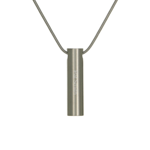 The Pewter Cylinder Memorial Necklace, available at Magnolia Cremations, is a sleek stainless steel pendant designed for subtle remembrance. Its modern cylindrical shape discreetly holds a nominal amount of ashes, keeping your loved one close. This pendant features custom engraving, as shown with "Pat Smith" inscribed, allowing for personalization. A matching chain is included, making it a timeless and meaningful keepsake.