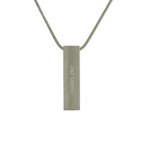The Pewter Pillar Memorial Necklace, available at Magnolia Cremations, is a sleek stainless steel pendant with a modern brushed silver finish. This pillar-shaped design includes a hidden compartment to hold a nominal amount of ashes, offering a meaningful way to keep a loved one close. The necklace also features an engraving option, showcased in the image, for personalization and comes with a matching 19-inch chain.