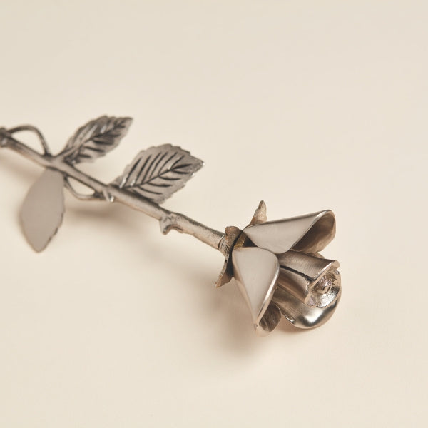 A detailed close-up of the Pewter Rose Keepsake from Magnolia Cremations, highlighting its polished silver petals and textured stem with intricate leaf detailing. This brass-crafted memorial piece is designed to hold a small portion of ashes, serving as a timeless tribute to a loved one.