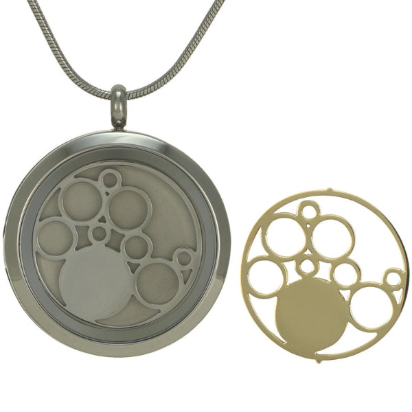 The Pewter Round Circles Pendant Necklace, available at Magnolia Cremations, features a symbolic interlocking circle design, representing eternity and connection. This memorial necklace includes two interchangeable inserts, one in pewter and the other in 14k gold-plated bronze, allowing for a customized look. Designed to hold a small portion of ashes, it is crafted from stainless steel and comes with a matching 19-inch chain. Engraving is available for a personalized tribute to a loved one.