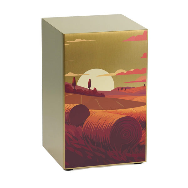 The Prairie Landscape in Bronze Memorial Urn, available at Magnolia Cremations, is a full-size stainless steel urn with a brushed bronze finish. The front panel showcases a warm-toned illustration of a prairie at sunset, featuring rolling hills, hay bales, and a golden sun casting a soft glow. This contemporary urn is part of the Life Canvas Series and offers engraving options for personalization.