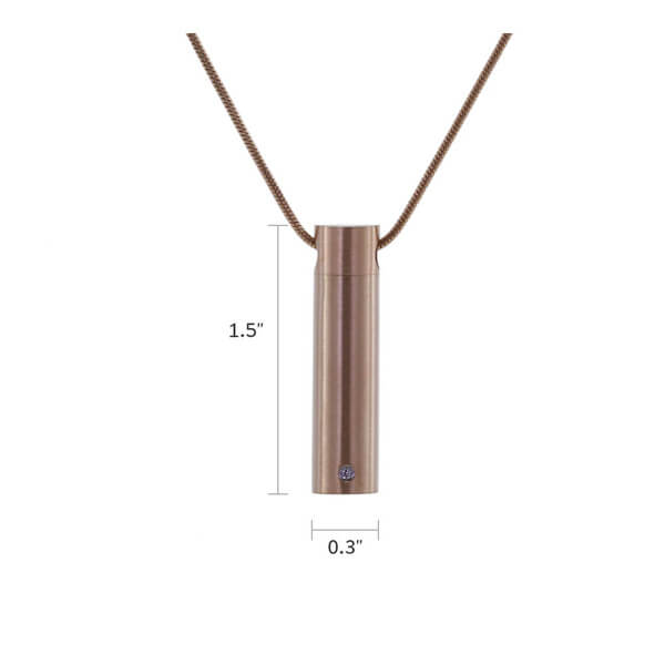 The Rose Cylinder with Cubic Zirconia Necklace, available at Magnolia Cremations, is displayed here with precise dimensions for reference. Measuring 1.5 inches in height and 0.3 inches in width, this rose gold-finished stainless steel pendant features a sleek cylindrical design with a single cubic zirconia accent. Designed to hold a small portion of ashes, this discreet and elegant piece comes with a matching chain and offers engraving options for a personal touch.
