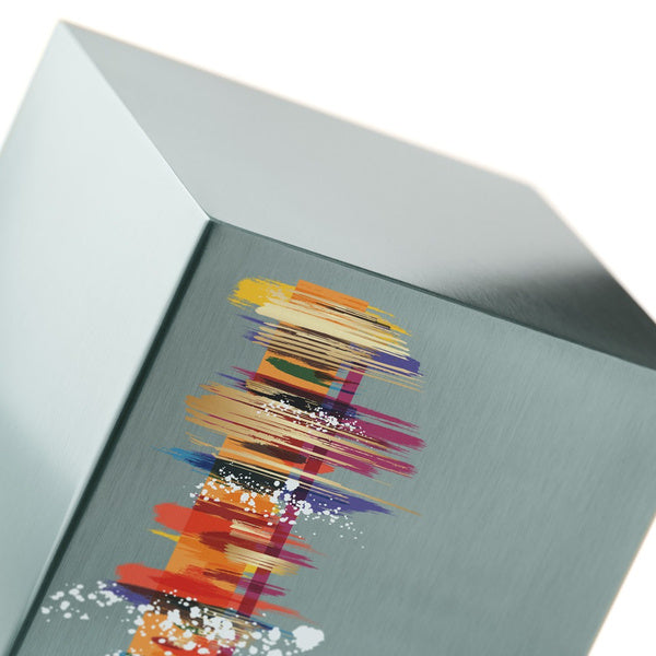 A close-up of The Artist in Pewter Memorial Urn, available at Magnolia Cremations, highlighting its brushed stainless steel surface and vibrant abstract design. The detailed artwork features bold strokes of red, orange, purple, and white, creating a striking contrast against the metallic pewter finish. The smooth edges and reflective material enhance the modern aesthetic of the urn.