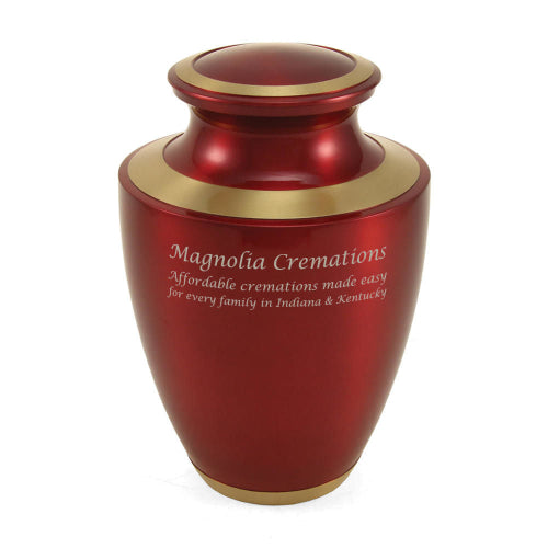 The Trinity Crimson Memorial Urn, available at Magnolia Cremations. This full-size brass urn features a deep crimson high-gloss finish with gold accents along the lid, neck, and base. The front showcases an engraved Magnolia Cremations inscription, highlighting its availability through their services.