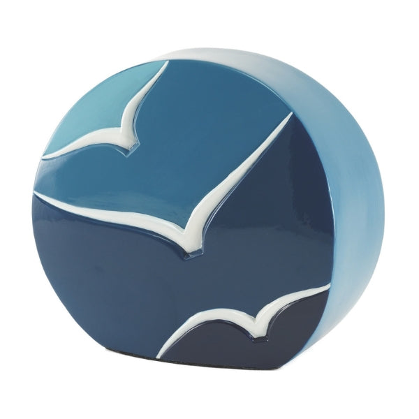 The Windham Going Home Glossy Blue Memorial Urn, available at Magnolia Cremations, features a modern, curved design with a glossy blue gradient finish. White bird silhouettes in flight are hand-painted on the surface, symbolizing peace and remembrance. Personalization options are available.