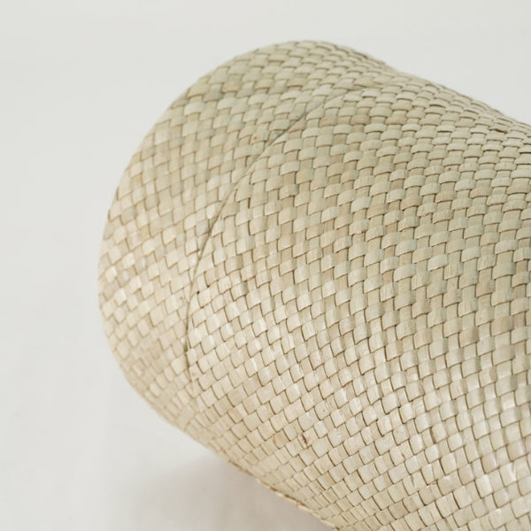 A close-up view of the Woven Naturals Tan Palm Memorial Urn, available at Magnolia Cremations. The image highlights the urn’s intricate handwoven palm leaf construction in a soft tan hue. The weave pattern is tightly interlaced, creating a sturdy yet natural texture. A subtle seam is visible where the lid meets the body, seamlessly blending into the design for a cohesive and organic appearance.