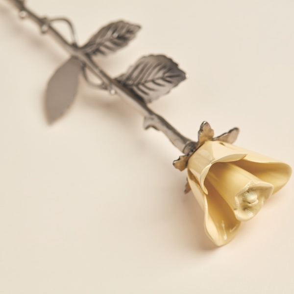 A close-up of the Yellow Rose Keepsake from Magnolia Cremations, showcasing its delicate pale yellow petals with a smooth, polished finish. The detailed pewter-toned stem and textured leaves add to its elegant design. Crafted from brass, this keepsake is designed to hold a small portion of ashes, offering a timeless and meaningful tribute to a loved one.