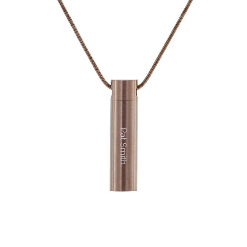 The Rose Cylinder with Cubic Zirconia Necklace, available at Magnolia Cremations, is shown here with a custom engraved name for a personalized touch. This rose gold-finished stainless steel pendant features a sleek cylindrical design, providing a discreet and elegant way to carry a small portion of a loved one’s ashes. A single cubic zirconia accent adds a subtle sparkle. The pendant comes with a matching chain, and engraving options are available to create a meaningful keepsake.