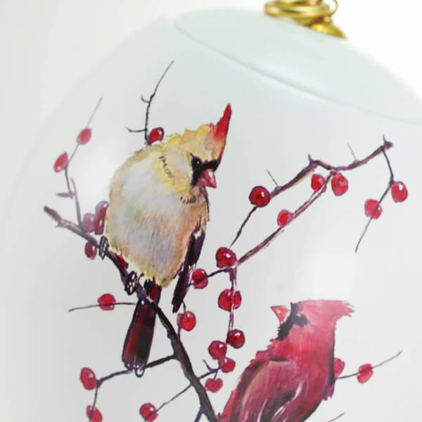 Decorative memorial cremation urn with cardinals and berries on a white background