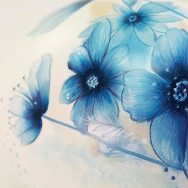 Close-up of ceramic memorial cremation urn with blue flowers with a soft focus background