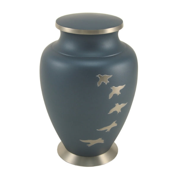 The Aria Ascending Memorial Urn from Magnolia Cremations is a full-size brass urn featuring a matte navy blue finish accented with silver-tone birds in flight. This elegant design symbolizes peace and freedom, making it a meaningful tribute to a loved one. With a sturdy nickel-plated base and lid, the urn provides a secure and timeless resting place. Suitable for holding the ashes of an individual weighing up to 200 lbs, it can also be engraved for a personalized touch.