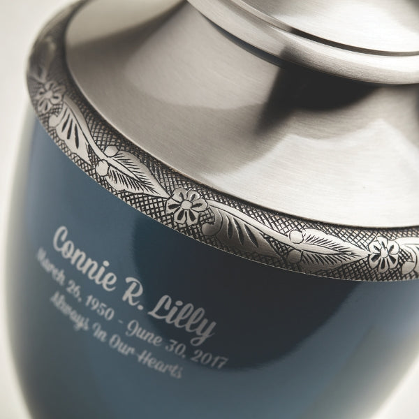 Deep blue cremation urn made of brass with a subtle sheen and delicate floral etchings.