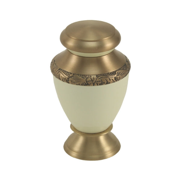 The Artisan Pearl Keepsake Urn, available at Magnolia Cremations, is a small, elegant urn with a soft white body and gold-tone brass accents. Its design features intricate hand-engraved detailing along the upper rim and lid, adding a timeless touch. Crafted from aluminum and brass, this keepsake urn is designed to hold a small portion of ashes, allowing multiple family members to cherish a loved one’s memory.