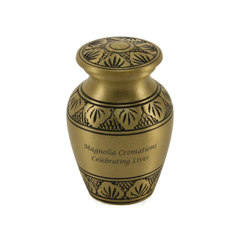 The Athena Bronze Keepsake Urn, available at Magnolia Cremations, is a small, traditional urn with a warm bronze finish and detailed black leaf engravings encircling its body and lid. The urn features an engraved message, highlighting the option for personalization. Designed to hold a small portion of ashes, this keepsake provides a way for loved ones to share in remembrance and keep a cherished connection.