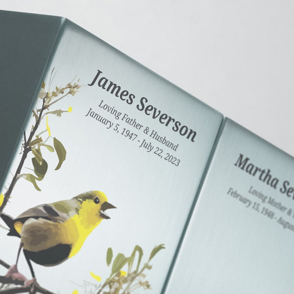 Close-up view of Life Canvas Birds Pewter Companion Urns, showcasing the brushed stainless-steel finish and artistic songbird illustrations. Engraving is available as a personalization option. Designed for couples or loved ones to be displayed together. Secure bottom panel closure with four screws. Each urn has a 200 cubic inch capacity.