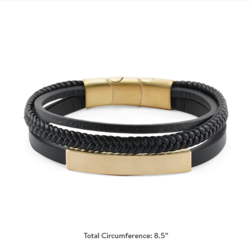 The Brass/Black Triple Band Leather Bracelet, available at Magnolia Cremations, is a modern memorial piece with a total circumference of 8.5 inches. It features three black leather bands—one smooth, one braided, and one accented with a gold-tone bar that can be engraved for personalization. The bracelet secures with a gold-tone stainless steel clasp and discreetly holds a small portion of ashes, offering a stylish and meaningful way to keep a loved one close.