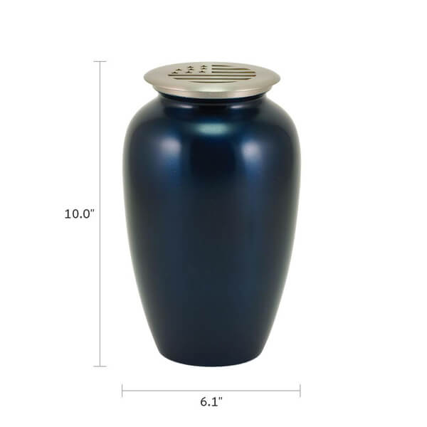 A dark blue scattering urn with a silver-toned lid that features a cutout design of the American flag. The image includes dimensions, showing the urn is 10.0 inches tall and 6.1 inches wide at its widest point.