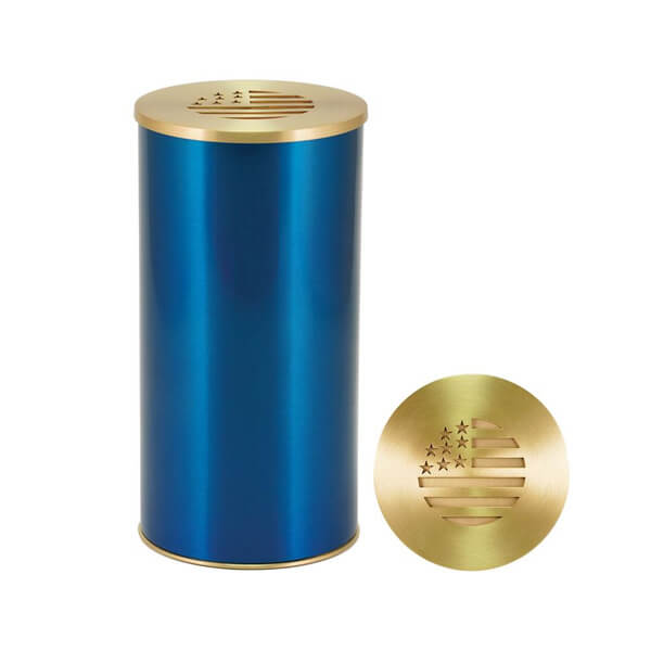 A cylindrical scattering urn with a metallic blue body and gold-colored lid and base. The lid features a cutout design resembling the American flag with stars and stripes. A close-up view of the lid is shown beside the urn.