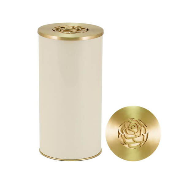 Cream-colored cylindrical scattering urn with a metallic gold lid. The lid features a decorative rose-shaped cutout design. An additional view of the lid is shown beside the urn, highlighting the intricate rose pattern