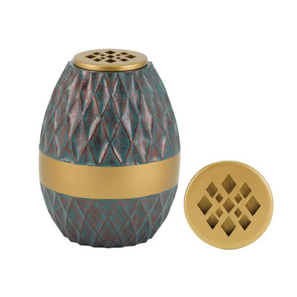Decorative scattering urn with a textured, diamond-patterned body in teal and reddish tones, featuring a wide gold band around the middle. The urn has a removable gold lid with a lattice-style cutout design, shown separately beside it. This urn can be converted into a flower vase.