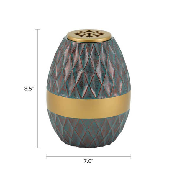 Decorative scattering urn with a textured diamond-patterned surface in teal and reddish tones, featuring a wide gold band around the middle and a gold lid with lattice cutouts. The urn is shown with dimensions: 8.5 inches tall and 7.0 inches wide.