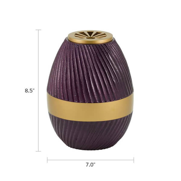A purple, ribbed scattering urn with a gold lid and central gold band is shown with dimensions marked. The urn is 8.5 inches tall and 7.0 inches wide at its widest point.