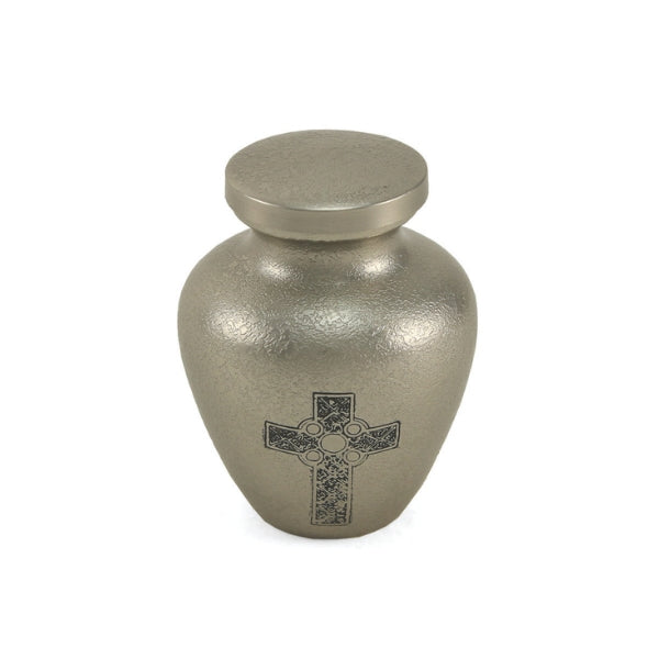 The Celtic Cross Keepsake Urn, available from Magnolia Cremations, features a textured silver finish with an intricate black Celtic Cross engraving on the front. Crafted from brass, this small urn is designed to hold a portion of ashes, providing a meaningful way for loved ones to share in remembrance.