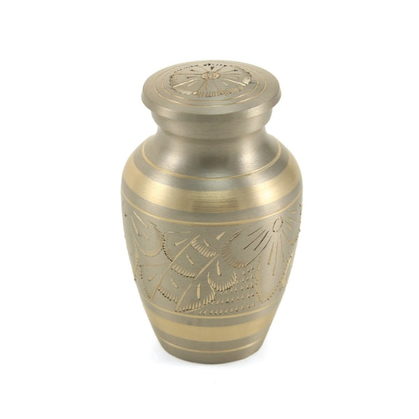 The Classic Platinum Keepsake Urn, available from Magnolia Cremations, is a small, elegant urn crafted from brass with a brushed silver finish and gold-tone accents. Its intricate hand-engraved floral design adds a timeless touch. This keepsake urn is designed to hold a small portion of ashes, allowing families to share a lasting tribute to their loved one.