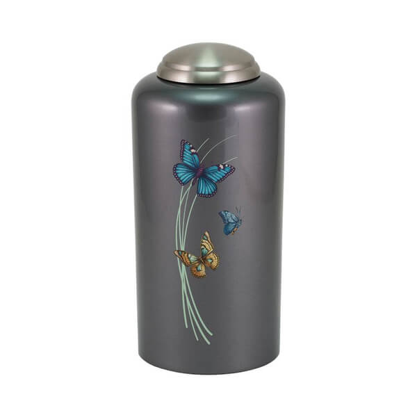 Dark gray cremation urn with a metallic finish and domed lid, featuring a design of three colorful butterflies—blue, teal, and orange—flying around soft green curved lines resembling blades of grass.