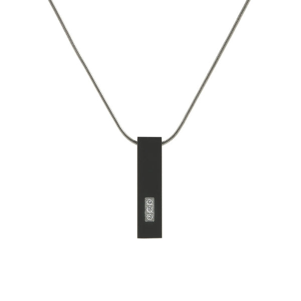 The Onyx Pillar w/ Cubic Zirconia Memorial Necklace is a modern, black stainless steel pendant with a sleek rectangular design. It features three cubic zirconia stones set in a vertical row, adding a touch of elegance. The pendant has a discreet compartment for holding a small portion of ashes and comes with a matching 19-inch chain. Engraving is available for personalization.