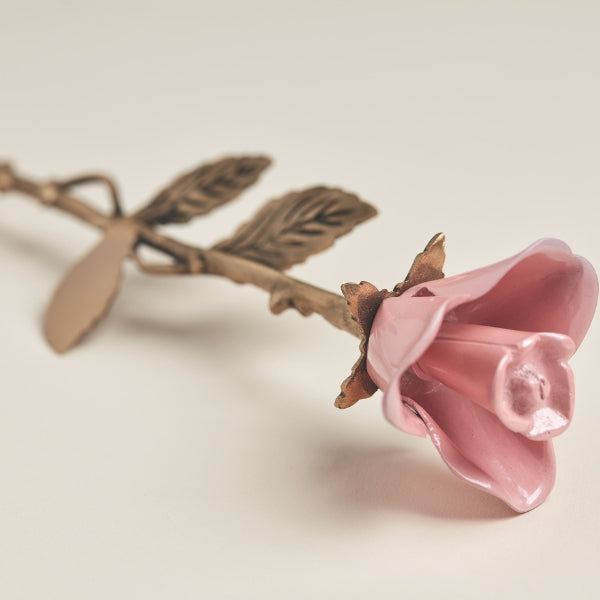 A close-up view of the Pink Rose Keepsake from Magnolia Cremations, showcasing its delicate brass construction with a soft pink rose and a gold-toned stem. The intricately detailed petals and textured leaves enhance its elegant design, serving as a meaningful tribute to a loved one.