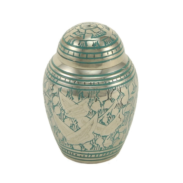 The Traditional Going Home Keepsake Urn, available at Magnolia Cremations, is a small brass urn featuring a polished silver finish with intricate green hand-engraved details. The urn is adorned with a graceful bird motif, symbolizing peace and a spiritual journey. Its rounded shape and secure lid provide a classic and timeless tribute. Designed to hold a small portion of ashes, this keepsake offers a meaningful way for multiple family members to cherish their loved one’s memory.