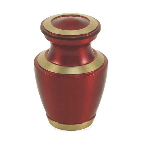 The Trinity Crimson Keepsake Urn, available at Magnolia Cremations, is a small brass urn with a bold crimson high-gloss finish, accented by gold-tone bands along the lid, base, and rim. Its sleek, contemporary design offers a sophisticated yet timeless tribute. Crafted to hold a small portion of ashes, this keepsake allows loved ones to share and cherish a meaningful remembrance.