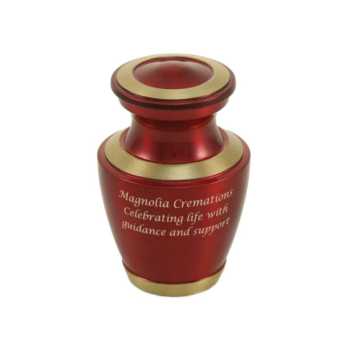 The Trinity Crimson Keepsake Urn, available at Magnolia Cremations, is a small, elegant urn with a deep crimson high-gloss finish and gold-tone accents along the lid, base, and rim. The urn features an engraved inscription, highlighting the option for personalization. Crafted from brass, this keepsake urn is designed to hold a small portion of ashes, allowing family members to keep a meaningful remembrance of their loved one.