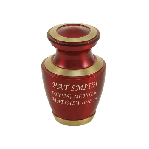 The Trinity Crimson Keepsake Urn, available at Magnolia Cremations, is a small, beautifully crafted urn featuring a striking crimson high-gloss finish with gold-tone accents on the lid, rim, and base. The urn includes an engraved inscription, demonstrating the option for personalization. Made from brass, this keepsake urn is designed to hold a small portion of ashes, providing a cherished way to honor a loved one's memory.